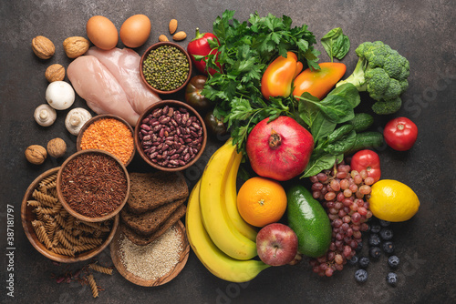 Whole grains and pasta, variety of vegetables, fruits and protein products on brown background. Balanced nutrition for healthy diet and immune system