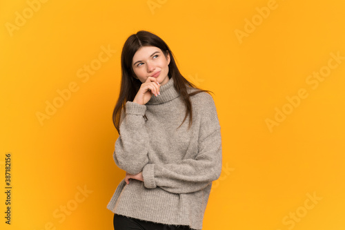 Young Ukrainian girl isolated on yellow background and looking up © luismolinero