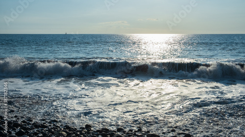 Waves on the shore of a black pebble beach