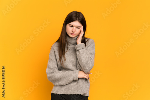 Young Ukrainian girl isolated on yellow background with headache © luismolinero