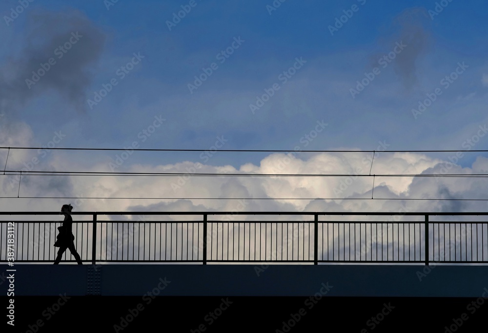 clouds over a bridge with silhouetted person