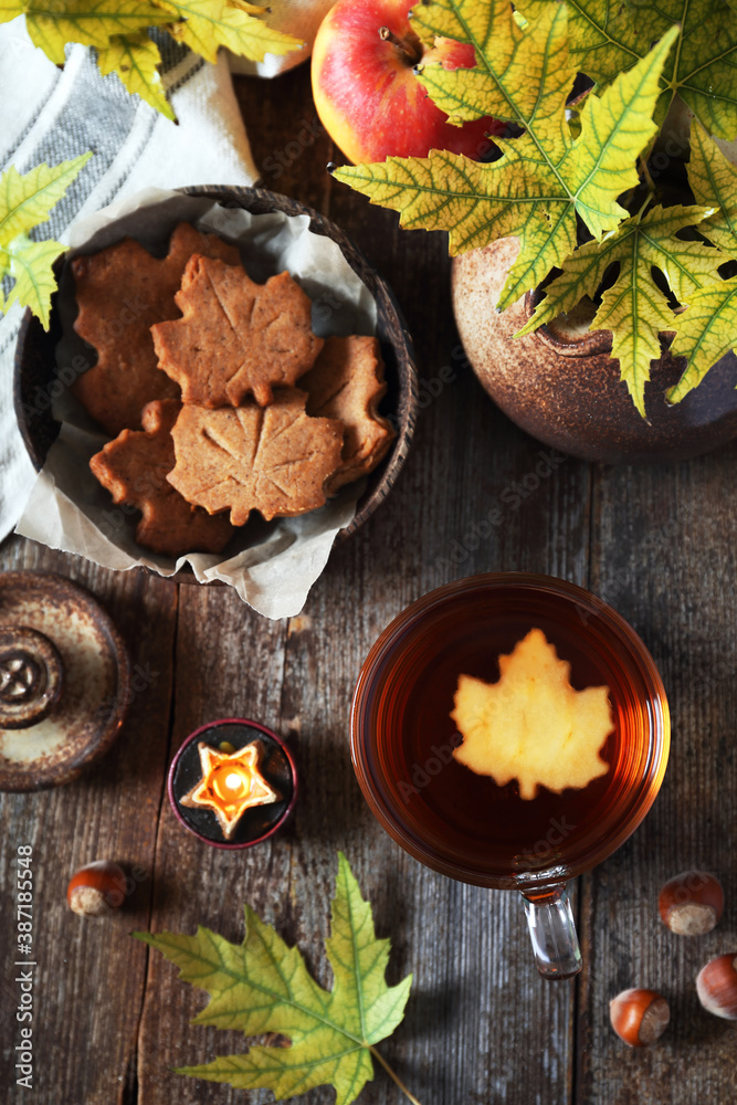 Autumn food: cinnamon cookies in form of maple leaves, cup of tea, apples and yellow leaves