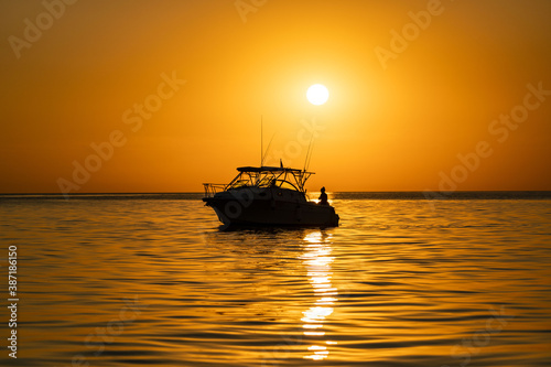 sunset at sea during calm weather with a view of a large yacht