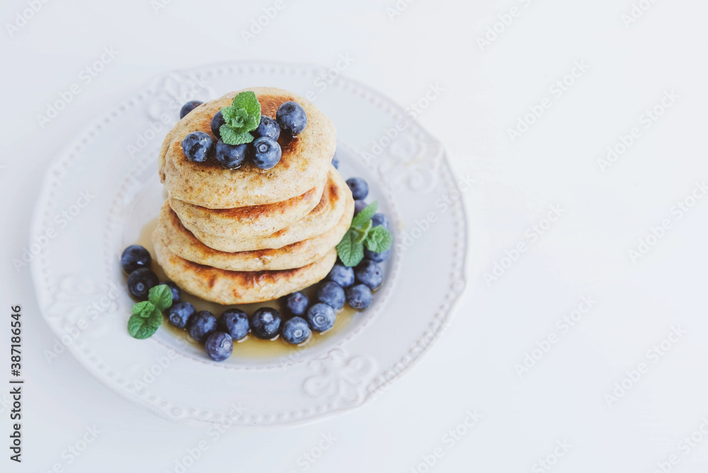Stack of homemade small thick pancakes served with fresh blueberries. Stack of homemade small thick pancakes served with fresh blueberries.