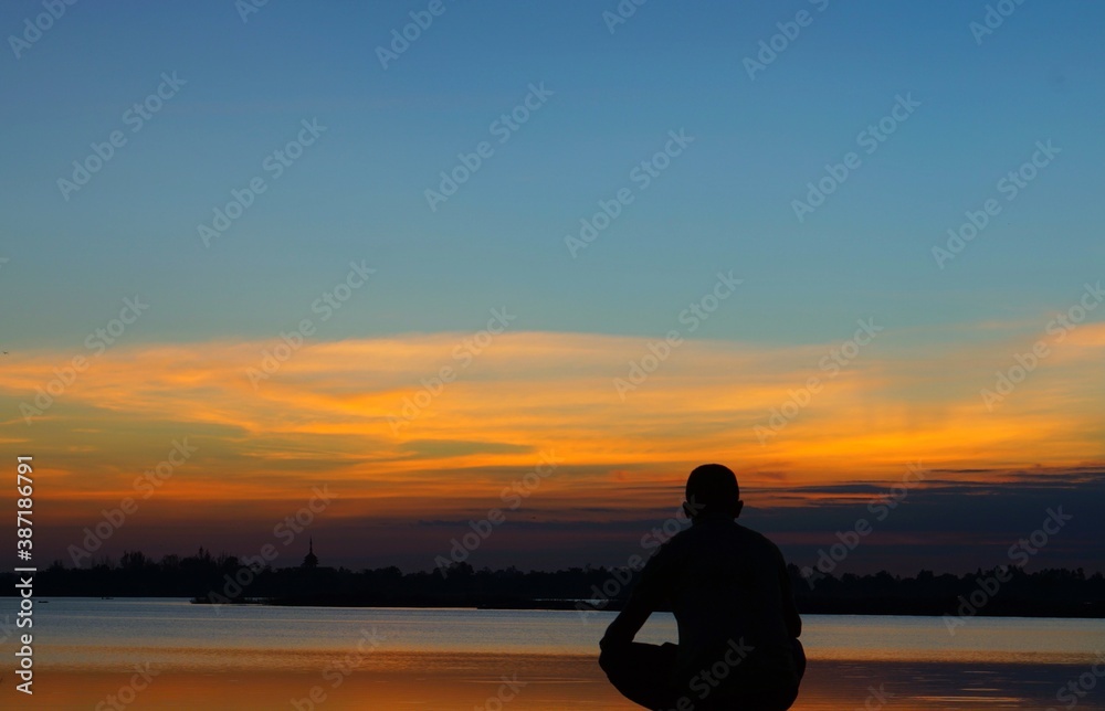 man standing by the river looking at the sunset sky. Using a silhouette technique