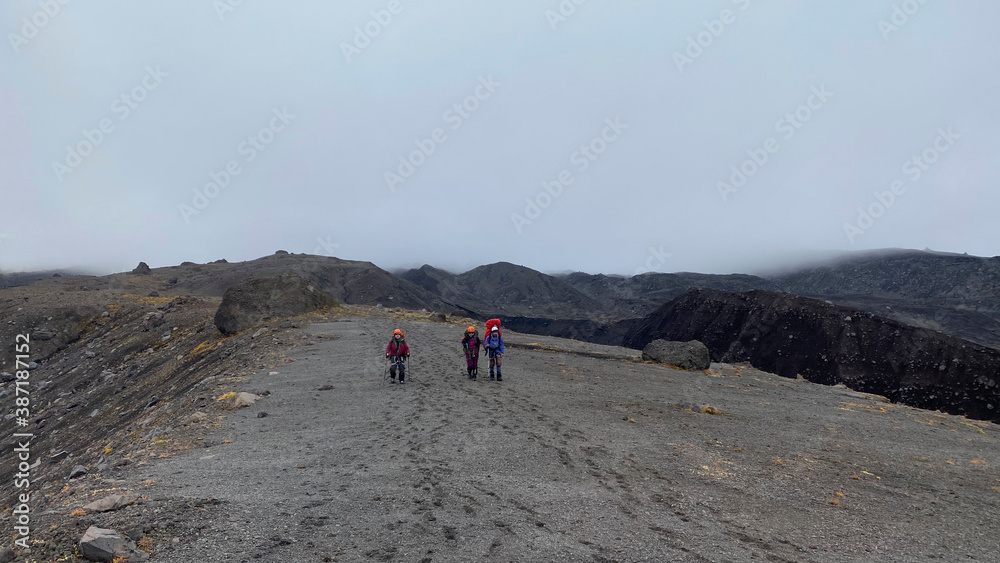 Three tourist climbers walk through the lava fields of central Kamchatka.