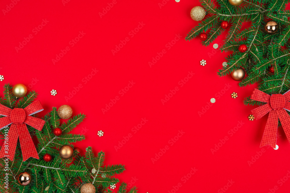 Top view of Christmas card made of fir tree, bows, golden decorations, confetti, snowflakes on red background with copy space. Happy New Year greetings. Festive winter holidays backdrop.  Flat lay. Ve