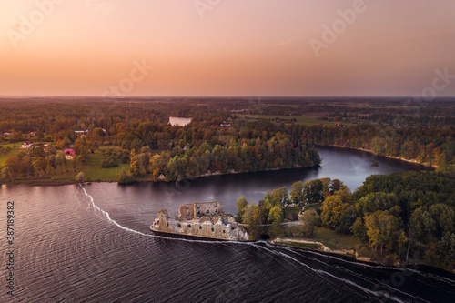 Aerial view of Koknese castle ruins at colorful sunset. Medieval ruins on the shore of river surrounded by forest. 