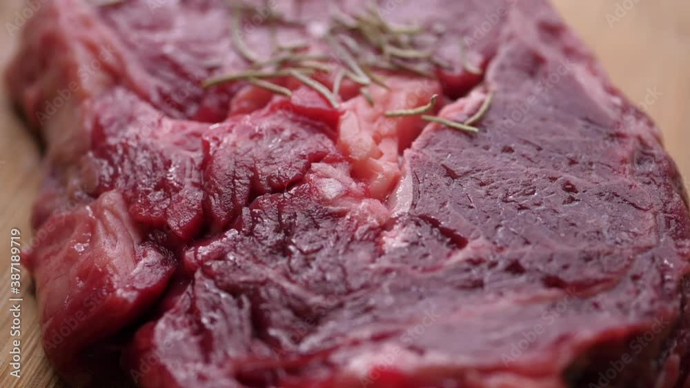 Dried rosemary Falling On Raw beef Steak On cutting Board Dried rosemary Falling On Raw beef Steak On cutting Board