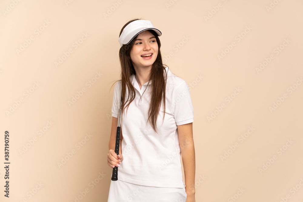 Young Ukrainian golfer girl isolated on beige background looking to the side and smiling Young Ukrainian golfer girl isolated on beige background looking to the side and smiling