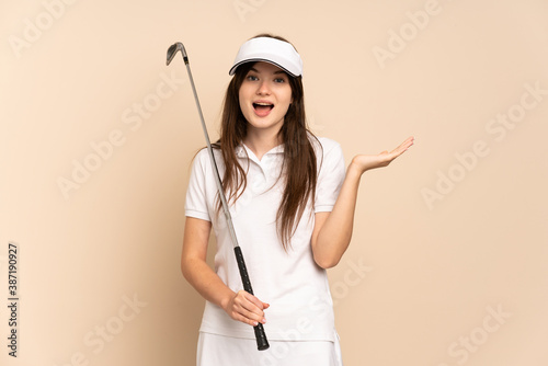 Young Ukrainian golfer girl isolated on beige background with shocked facial expression photo