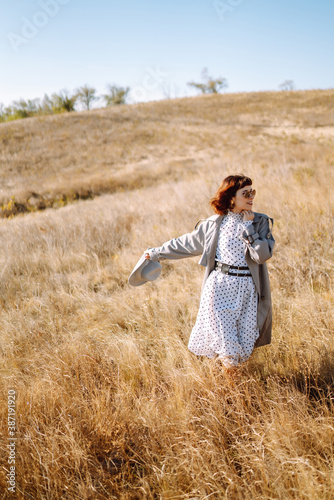 Stylish woman walking in autumn field. Relaxation, enjoying, solitude with nature.