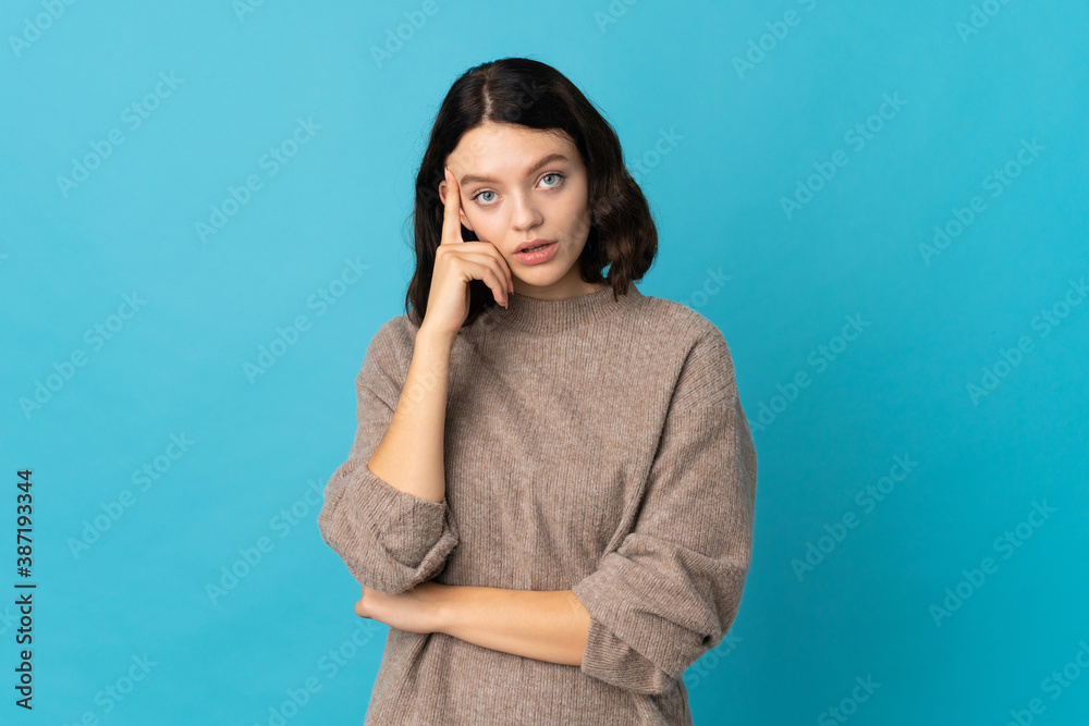 Teenager Ukrainian girl isolated on blue background thinking an idea Teenager Ukrainian girl isolated on blue background thinking an idea