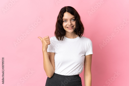Teenager Ukrainian girl isolated on pink background pointing to the side to present a product