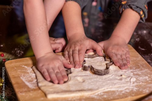 Children cut out cookies from raw dough with a cookie cutter.