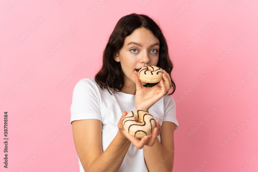 Teenager Ukrainian girl isolated on pink background holding a donut Teenager Ukrainian girl isolated on pink background holding a donut
