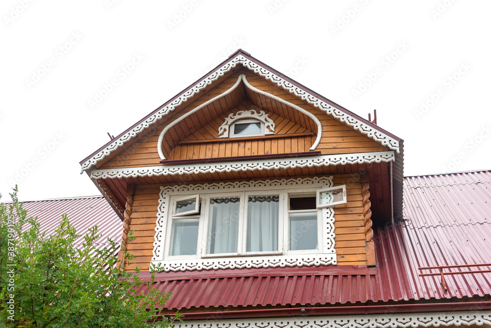 Retro mansard with large decorated window on red roof of traditional Russian country house in small village against cloudy sky on nice sunny day low angle shot. Retro mansard with large decorated window on red roof of traditional Russian country house in small village against cloudy sky on nice sunny day low angle shot.
