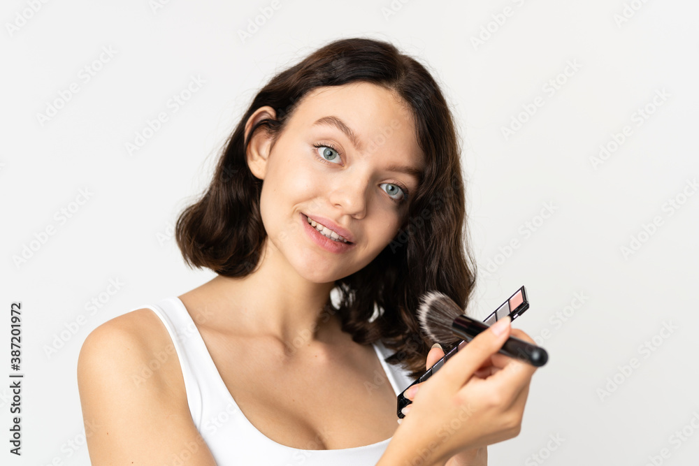 Teenager Ukrainian girl isolated on white background with makeup palette and happy Teenager Ukrainian girl isolated on white background with makeup palette and happy
