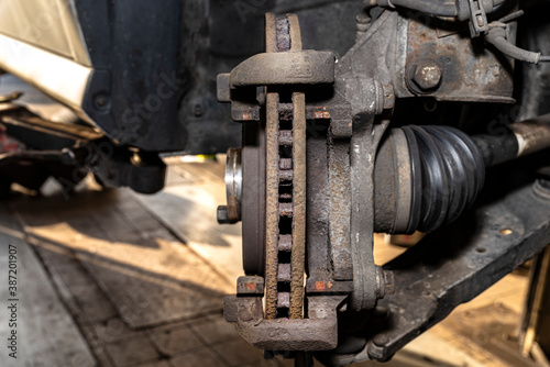 Old front brake disc without caliper and brake pads in the car  on a car lift in a workshop.