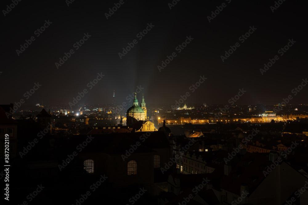 
the dome of the old church of St. Nicholas in the center of Prague at night and the surrounding architecture and light from the street lights