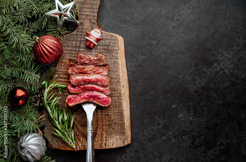 Different degrees of roasting of steak on a meat fork for Christmas on a background of a stone with a spruce and Christmas toys with copy space for your text
