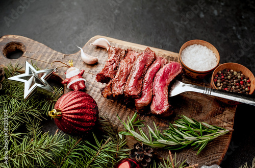 Different degrees of roasting of steak on a meat fork for Christmas on a background of a stone with a spruce and Christmas toys 