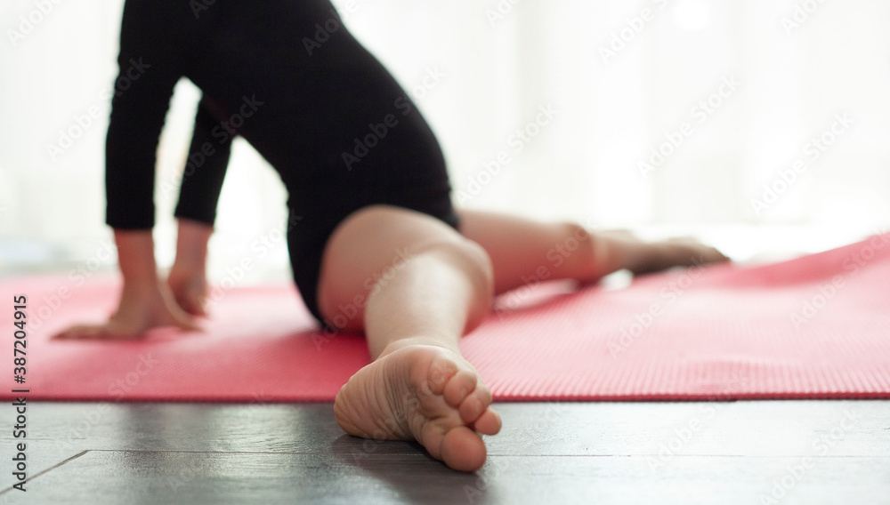 The little girl on the rug does a gymnastic exercise. legs of a little girl sitting in a twine. The foot is in focus, everything is out of focus. Quarantined classes The little girl on the rug does a gymnastic exercise. legs of a little girl sitting in a twine. The foot is in focus, everything is out of focus. Quarantined classes