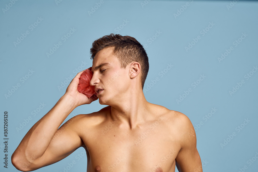 Young guy with a pink washcloth in his hand on a blue background skin care dermatology model cropped view