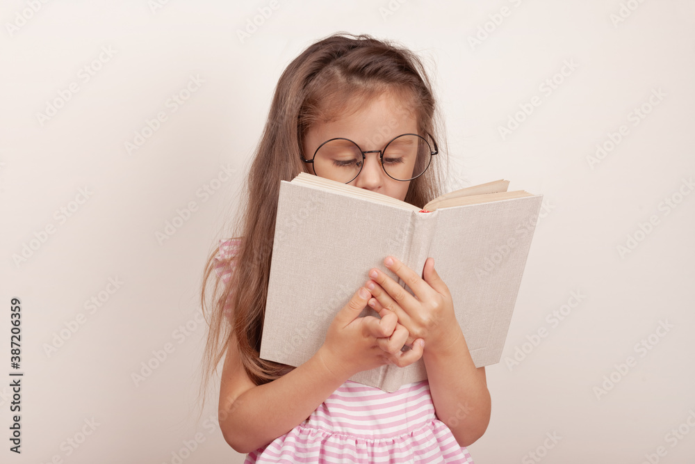 Little girl in glasses is reading a book. Little girl in glasses is reading a book.