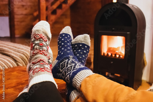 Feet in wool socks warming near fireplace in rustic cabin house. Cozy winter.