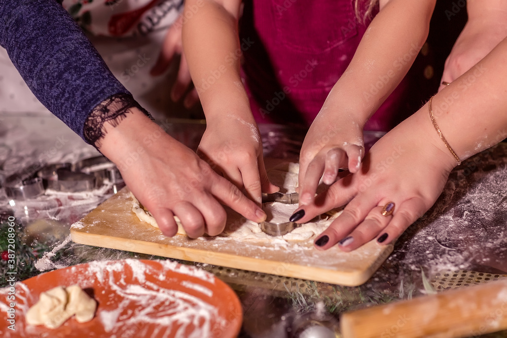 A girl with her mother and grandmother cut cookies from raw dough-a Christmas treat for Santa Claus.
