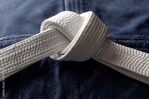 White judo, aikido or karate belt on blue budo gi. Concept is applicable to sports, business or education