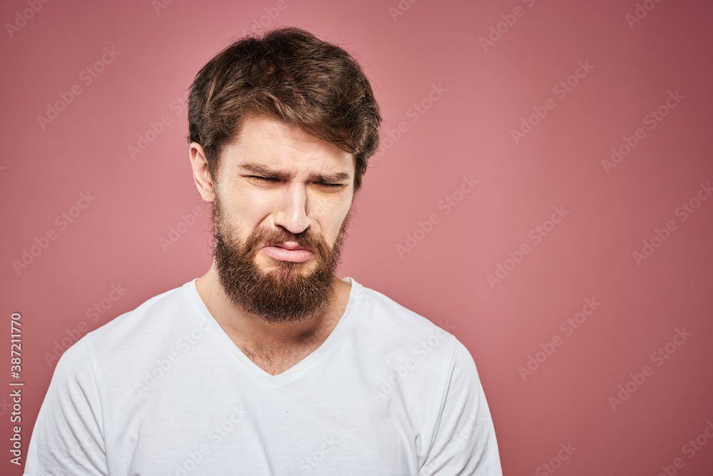 Emotional bearded man in white T-shirt discontent pink background Emotional bearded man in white T-shirt discontent pink background