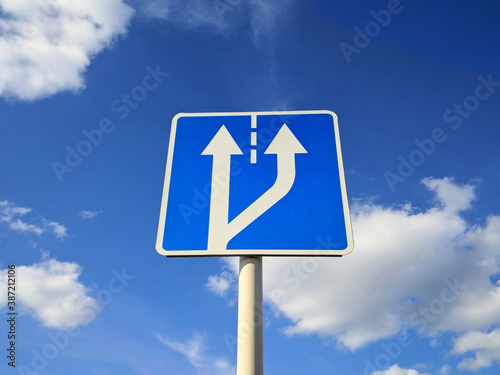 Road sign fork in the road on a background of blue sky in bright sunny weather © Pavel