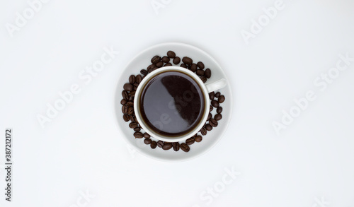 White Cup and saucer with coffee and coffee beans. Top view, white background. Free space for text.