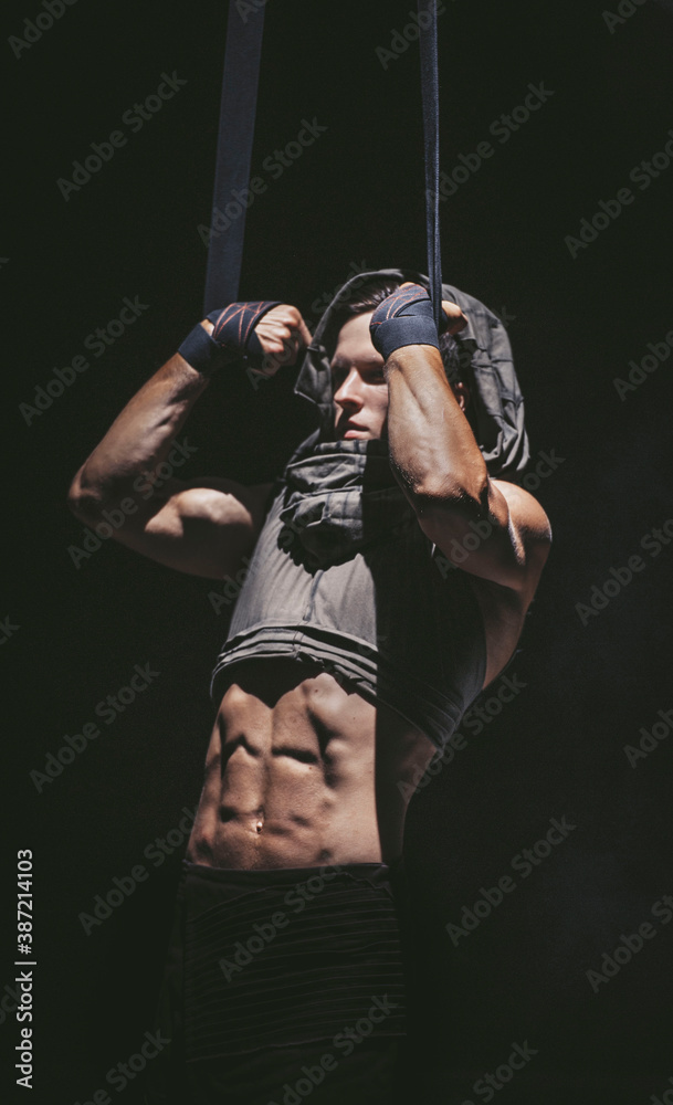 Young bodybuilder pull himself up on the ropes