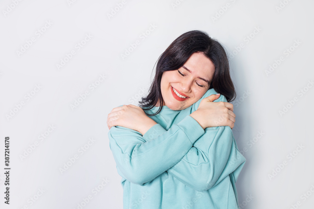 Portrait confident smiling woman holding hugging herself isolated gray wall background. Positive human emotion, facial expression, emotion, reaction, situation, attitude. Love yourself concept