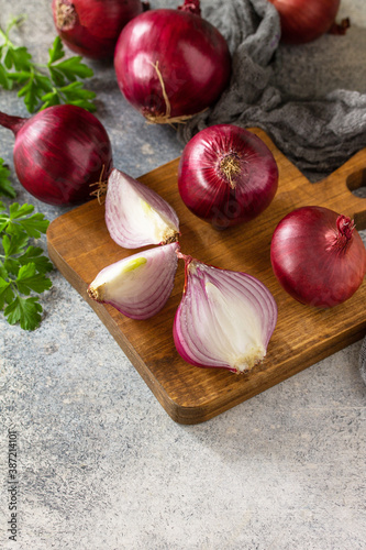 Purple Onions. Fresh whole purple onions and one sliced onion on a stone countertop. Copy space.