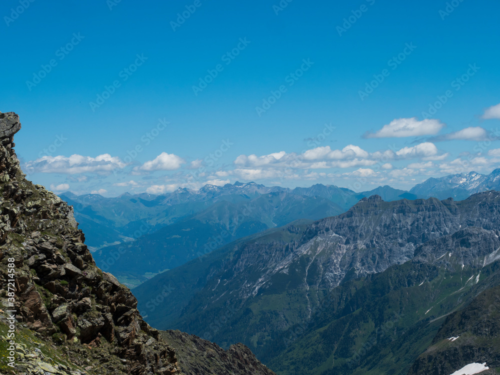 view from Simmingjochl mountain saddle on sharp snow-capped peaks at Stubai hiking trail, Stubai Hohenweg, Alpine landscape of Tyrol, Stubai Alps, Austria. Summer blue sky