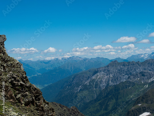view from Simmingjochl mountain saddle on sharp snow-capped peaks at Stubai hiking trail, Stubai Hohenweg, Alpine landscape of Tyrol, Stubai Alps, Austria. Summer blue sky