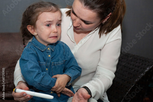 The little girl is crying and doesn't want to give the injection. Mom persuades her daughter to take an insulin injection. World Diabetes Day.