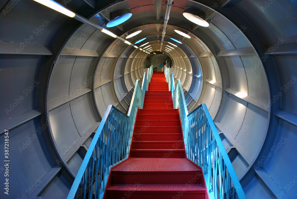 Fototapeta premium Staircase with red steps and blue railings in a futuristic corridor