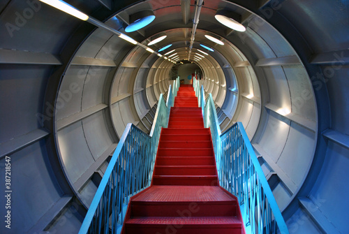 Staircase with red steps and blue railings in a futuristic corridor