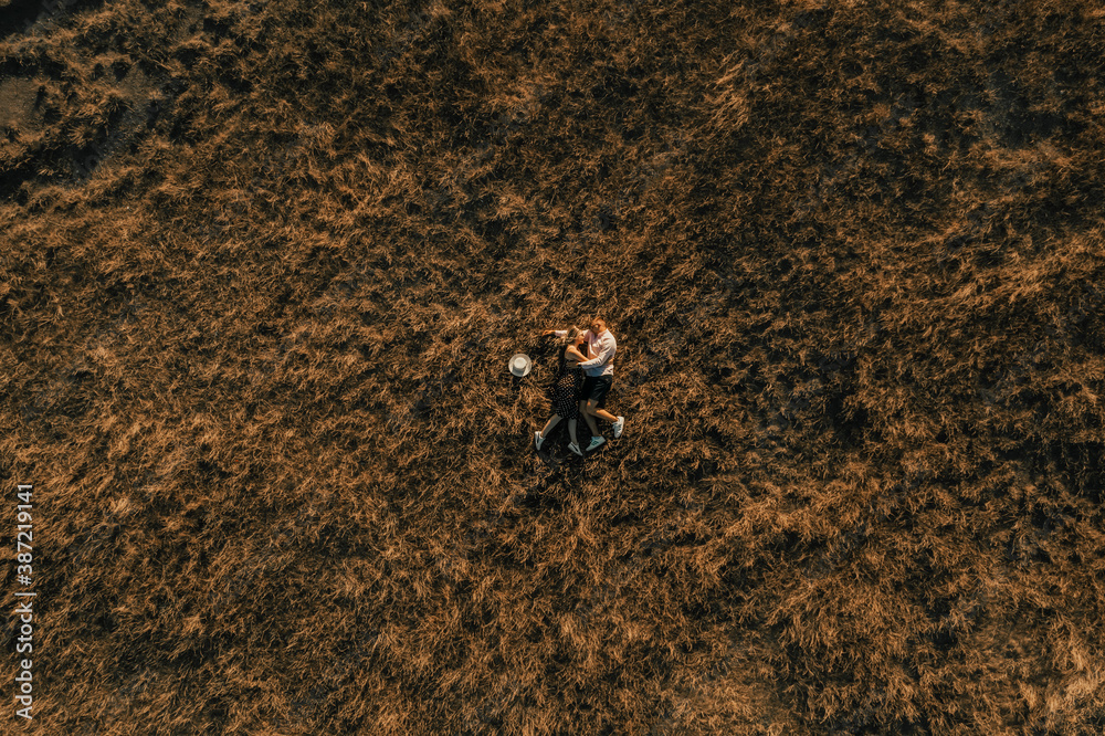 couple of people in love lies in high grass in meadow at sunset top view from drone