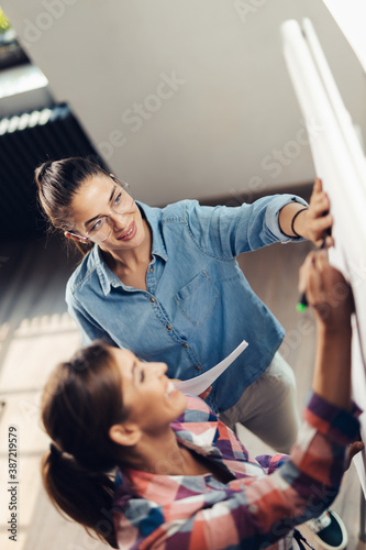 Above view of young businesswomen writing on whiteboard in the office