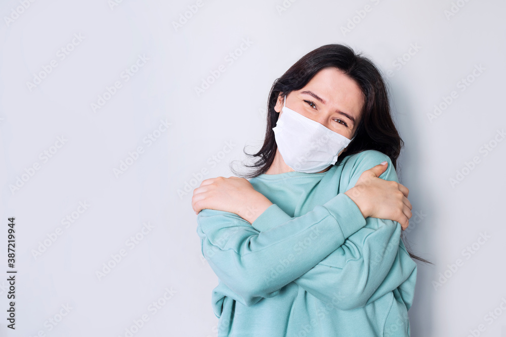 Young woman wearing coronavirus protection mask for covid-19 epidemic virus hugging oneself happy and positive, smiling confident. Self love and self care Young woman wearing coronavirus protection mask for covid-19 epidemic virus hugging oneself happy and positive, smiling confident. Self love and self care