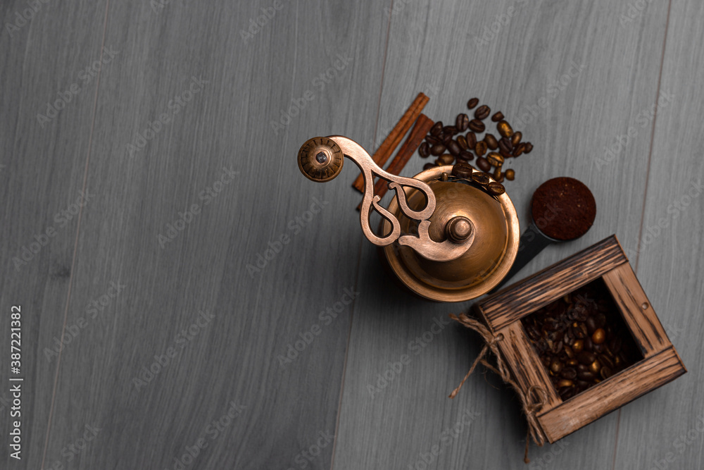 Manual vintage coffee grinder with coffee beans in the box and cinnamon sticks  on wooden surface