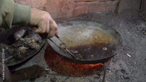 Elderly man in his workshop plates the copper bowl with tin. Tinsmith covering the copper object with tin over fire photo