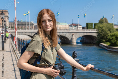 Canvas Print Young blonde girl in a green summer dress with a professional camera stands near