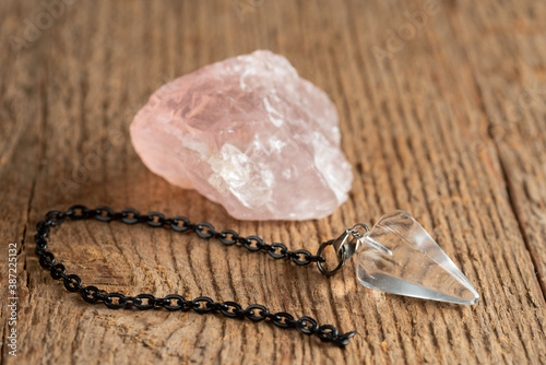 The pendulum on a chain with a natural crystal on a background of wood texture photo